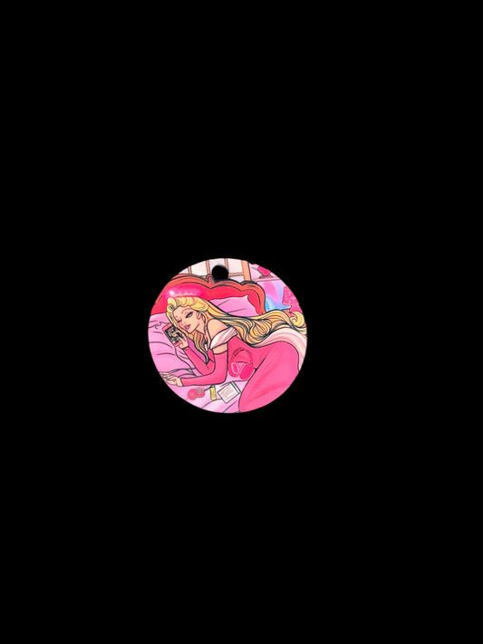 Round Stoned Beauty Keyring with double-sided glossy print featuring cannabis culture inspired artwork of a blonde woman in pink lounging on a bed.